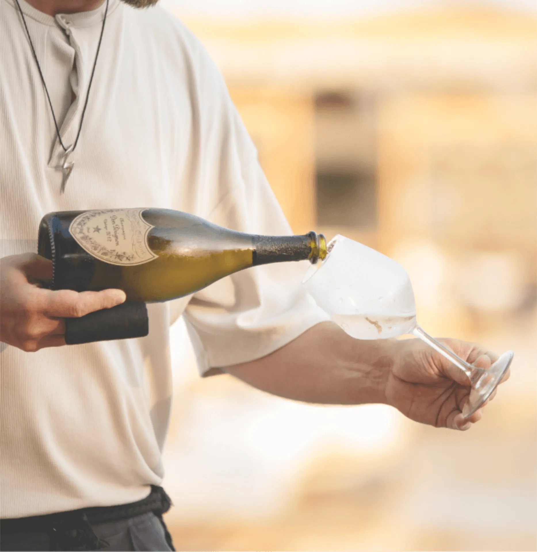 A man in white clothing pouring wine into glass